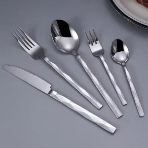 Hammered stainless steel flatware set including knife, dinner fork, salad fork, soup spoon, and dessert spoon with modern textured handles