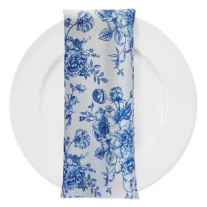 Elegant French Toile linen napkin in blue and white floral print, styled on a layered charger plate with pearls and navy sequin linen.