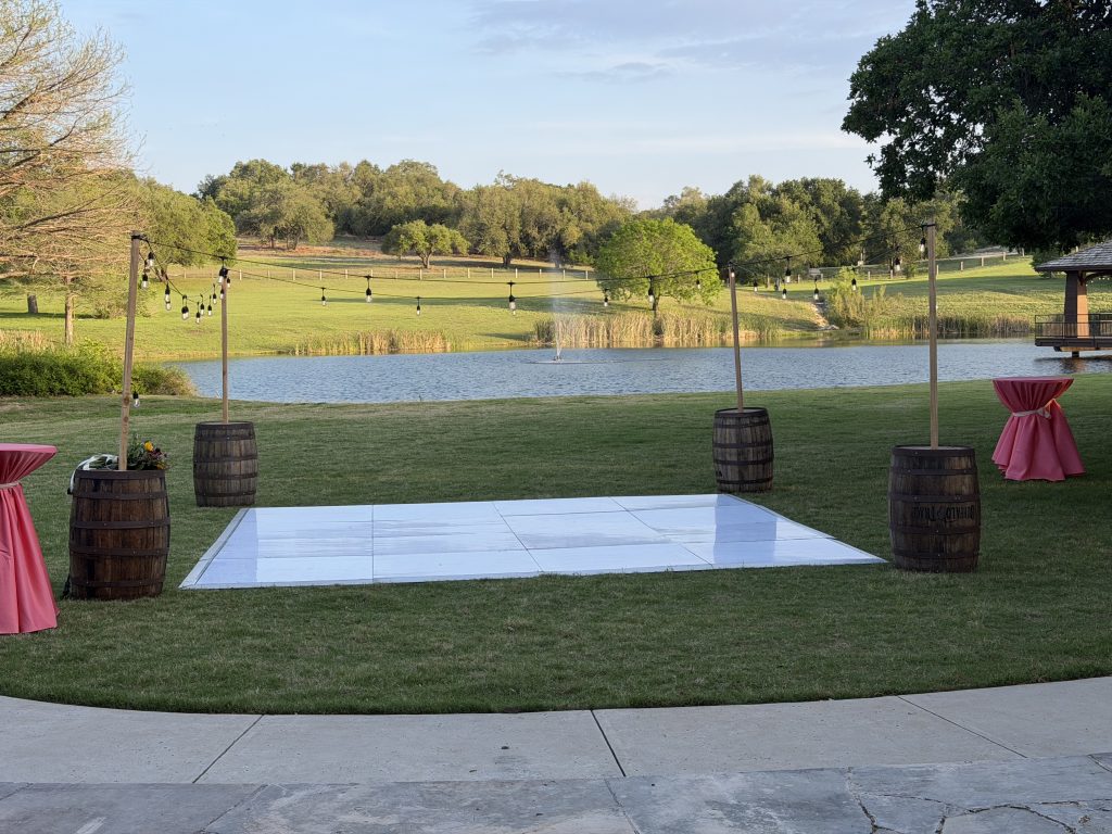 Outdoor wedding Rustic barrel pole lighting with overhead string lights for an outdoor event setup