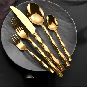 Elegant gold flatware set with fork, knife, and spoons on black plate, available for rent.