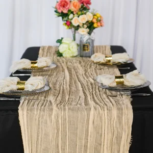 Champagne-colored premium cheesecloth table runner styled on a banquet table with elegant place settings and floral centerpiece.